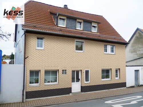 Ziegelfassade eines Hauses mit einer eleganten weißen Eingangstür.