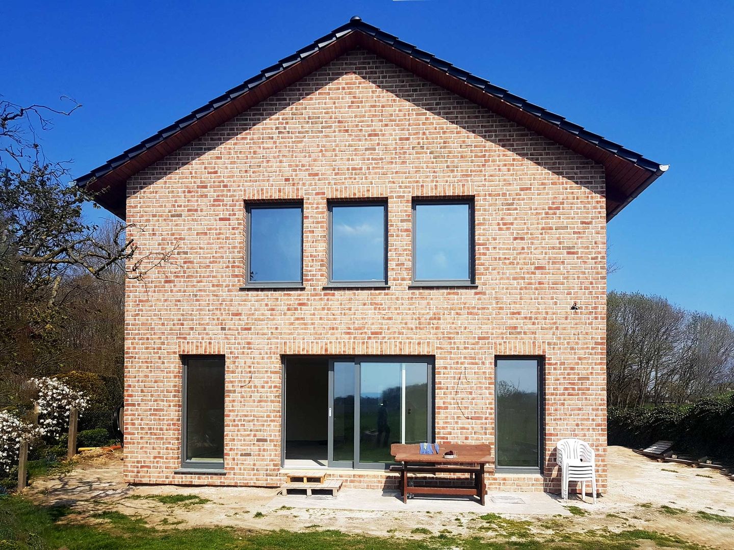 Ein Backsteinhaus mit einer Bank davor, umgeben von einer ruhigen, einladenden Umgebung.