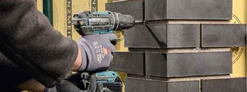 A man operates a drill while constructing a brick wall, demonstrating skilled craftsmanship in masonry work.