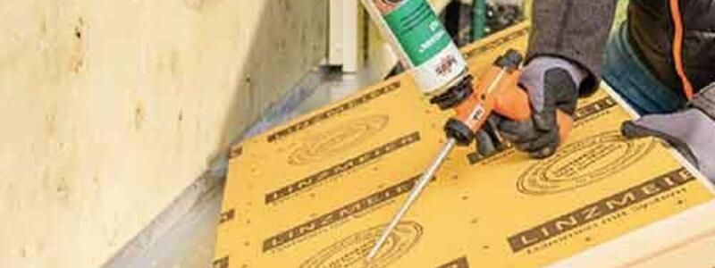 Un homme tient dans sa main un matériau isolant prêt à le fixer au mur.