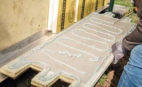 Un homme est en train de faire mousser le mur du fond du mur de façade à installer.