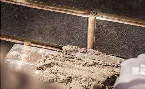 A man is grouting the brick façade.