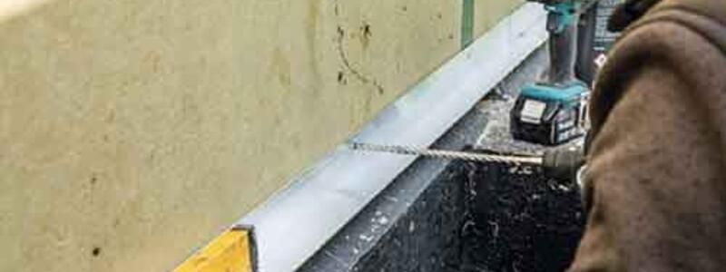 A man operates a drill to cut through a piece of metal