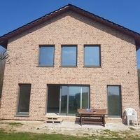 Ein Haus mit einem großen Fenster und einer Bank davor, die eine einladende Atmosphäre schafft.