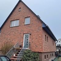 Ziegelfassade eines Hauses mit einem geparkten Auto davor.