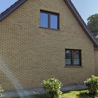 Ein Mann steht vor einem Haus mit einem Fenster, das die Außenansicht des Gebäudes zeigt.