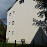 Ein Gebäude, umgeben von einem Zaun, der die Struktur klar abgrenzt und den Außenbereich definiert.