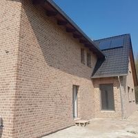 Ein Haus mit Solarpanelen auf dem Dach und einem weißen Stuhl im Vordergrund.