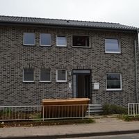 Ein Haus mit Ziegelfassade und einem Zaun umgibt das Grundstück, das eine einladende Atmosphäre schafft.