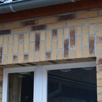 Ein Fenster mit weißem Rahmen, eingebettet in eine braune Ziegelmauer.