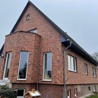 Ein Haus mit Ziegelfassade und einem davor geparkten Auto.