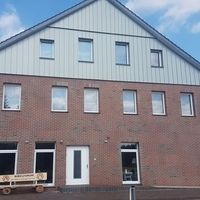 Ein Haus mit einer großen Ziegelmauer und mehreren Fenstern, das eine einladende Atmosphäre ausstrahlt.