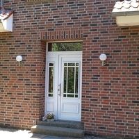 Eine weiße Tür an einem Backsteingebäude, die einen klaren Kontrast zur rauen Textur der Ziegel bietet.