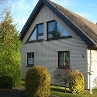 Ein kleines Haus mit einem schwarzen Dach, umgeben von einer ruhigen Landschaft.