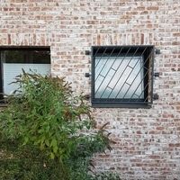 Ziegelmauer mit einem Fenster und einer Tür, die in die Wand integriert sind, zeigt eine rustikale Architektur.