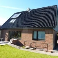 Ein modernes Haus mit Solarpanelen auf dem Dach, das die Nutzung von Solarenergie zur Reduzierung des ökologischen Fußabdrucks zeigt.