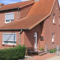 Ein Haus mit rotem Dach, umgeben von grüner Landschaft und klarem Himmel.