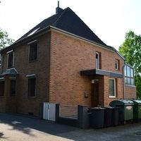 Großes Backsteingebäude mit solider Struktur und traditionellem Design, umgeben von einer grünen Landschaft.
