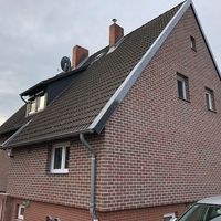 Ein Haus mit einem Ziegeldach und einem davor geparkten Auto.