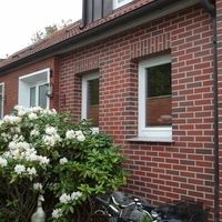 Ein Fahrrad steht vor einem Haus, während eine Blume davor blüht.