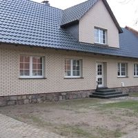 Ein Backsteinhaus mit einem schwarzen Dach, das in einer ruhigen Umgebung steht.