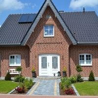 Ein Backsteinhaus mit einem Solarpanel auf dem Dach, das umweltfreundliche Energie erzeugt.