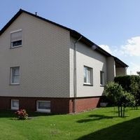 Ein Haus mit kleinem Garten und Zaun, umgeben von einer einladenden, grünen Landschaft.