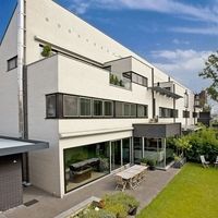 Modernes Haus mit großem Rasen und Terrasse, umgeben von einer einladenden Landschaft.