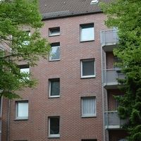 Großes Backsteingebäude mit einem geparkten Auto davor.
