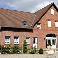 Ein Backsteinhaus mit einem großen Fenster und einer Tür, das eine einladende Atmosphäre ausstrahlt.