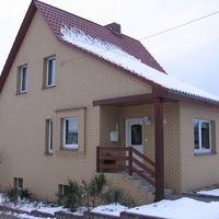 Ein Haus mit rotem Dach, umgeben von grüner Landschaft und klarem Himmel, strahlt Gemütlichkeit und Wärme aus.