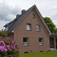 Ein Haus mit einer großen Backsteinfront und einem gepflegten Rasen davor.