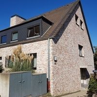 Ein Backsteinhaus mit einem großen Fenster und einer Tür, das eine einladende Atmosphäre ausstrahlt.