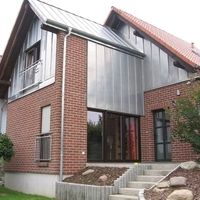 Ein Haus mit einem Metalldach, das in der Sonne glänzt und von einem klaren blauen Himmel umgeben ist.