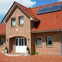 Ein Haus mit Solarpanelen auf dem Dach, das umweltfreundliche Energie erzeugt und nachhaltiges Wohnen fördert.