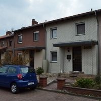 Eine Reihe von Häusern, die in einer urbanen Umgebung nebeneinander stehen, mit klaren Linien und unterschiedlichen Farben.